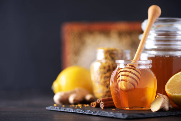 Alternative medicine concept. Ingredients for flu fighting natural hot drink. Copy space. Lemon, ginger, mint, honey, apple and spices on dark background - Photo, image