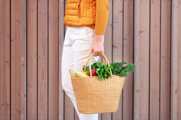 Zero marnotrawstwa z przestrzenią kopiowania. Kobieta trzyma słomkowy koszyk z warzywami, produktami. Ekologiczny klient. Zero odpadów, koncepcja bez tworzyw sztucznych. - Zdjęcie, obraz