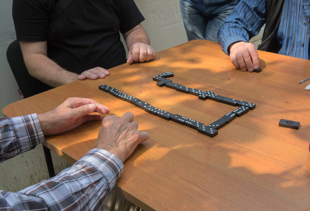 Im Hinterhof spielen mehrere Männer Dominosteine. Domino-Konzept. - Foto, Bild