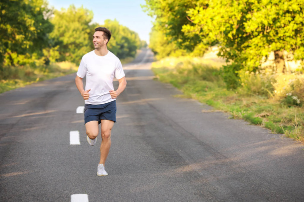Sporty young man running outdoors - 写真・画像