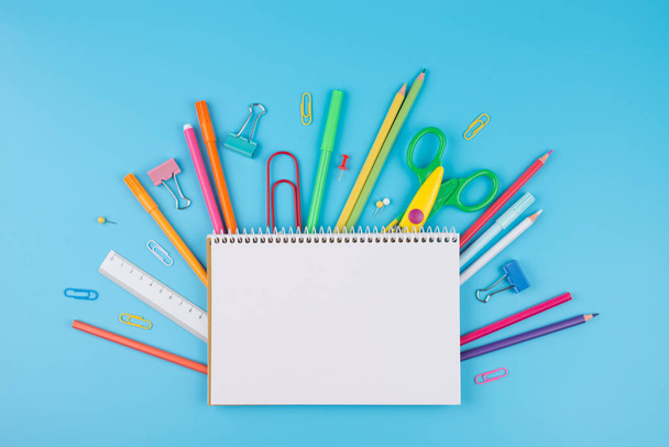 Materiali scolastici colorati e blocco note su sfondo blu
.  - Foto, immagini