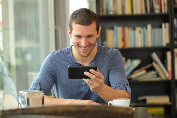 Boldog ember néz média-ra szúró telefon-ban egy büfé - Fotó, kép