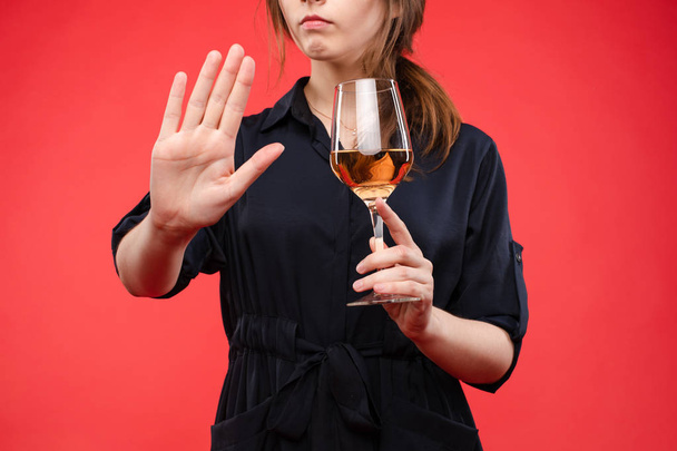Женщина с бокалом вина жесты руку с остановкой sign.Isolate на красном фоне
. - Фото, изображение