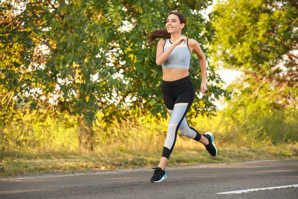 Sporty young woman running outdoors - Photo, Image