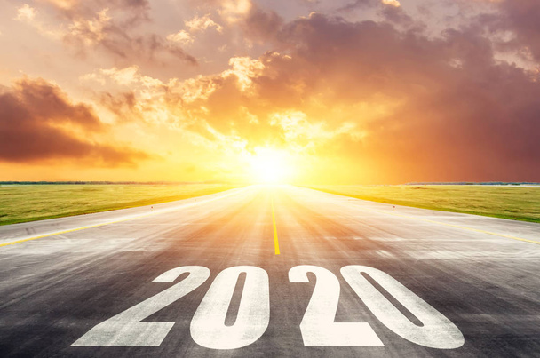 Camino asfalto carretera con la inscripción 2020 año con el sol naciente en la mañana. El concepto del comienzo de nuevos objetivos y asuntos
. - Foto, imagen