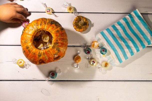 Halloween table. Child's hands. halloween pumpkin and candies. - Valokuva, kuva
