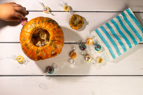 Halloween table. Child's hands. halloween pumpkin and candies. - Valokuva, kuva