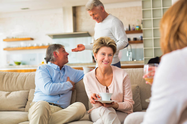 Mature friends drinking coffee at living room - Photo, image