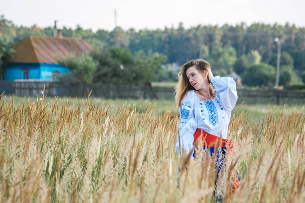 beautiful girl in national dress. bright national outfit. nature near the village. rustic motive. - Foto, afbeelding