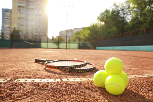 Теннисные мячи и ракетки на корте
 - Фото, изображение