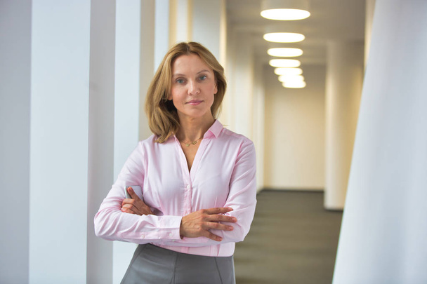 Portrait of confident businesswoman standing with arms crossed in corridor at office - Fotoğraf, Görsel