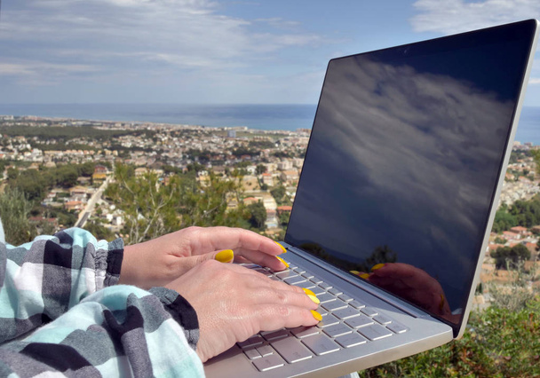 Kobiece ręce piszesz na klawiaturze laptopa, odbicie chmur na ekranie monitora - Zdjęcie, obraz