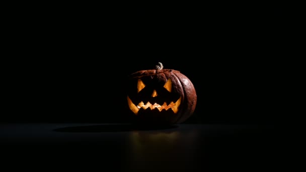 Halloween, orangefarbener Kürbis mit einem beängstigend leuchtenden Gesicht auf dunklem Hintergrund. Dicker grauer Rauch steigt auf und breitet sich über den schwarzen Tisch aus. Nahaufnahme einer Taschenlampe am Vorabend aller Heiligen - Filmmaterial, Video