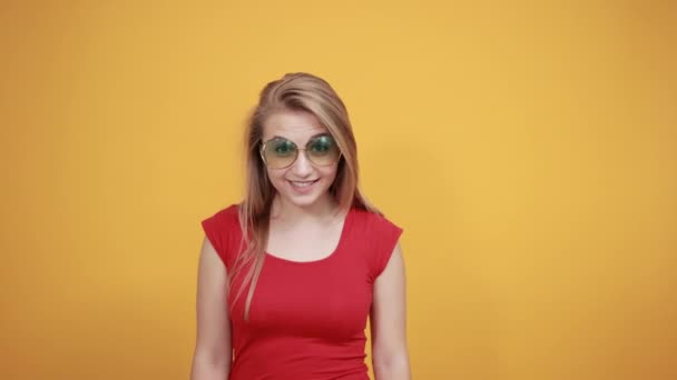 young blonde girl in red t-shirt over isolated orange background shows emotions - Кадри, відео