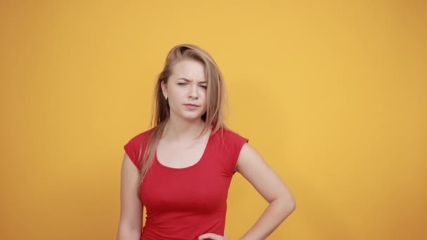 fiatal szőke lány, piros t-shirt át elkülönített narancssárga háttér mutatja érzelmek - Felvétel, videó