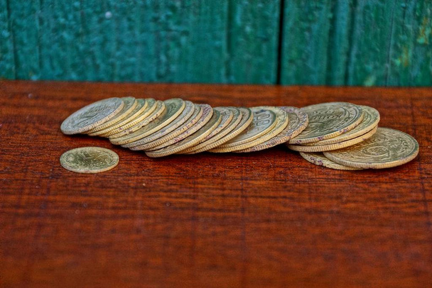 Un montón de viejas monedas amarillas soviéticas en una mesa roja junto a la pared verde
 - Foto, Imagen