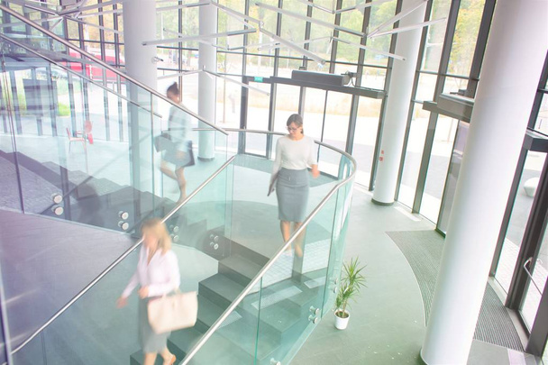 vista de ángulo alto de las mujeres de negocios caminando por las escaleras en el edificio de oficinas
 - Foto, Imagen