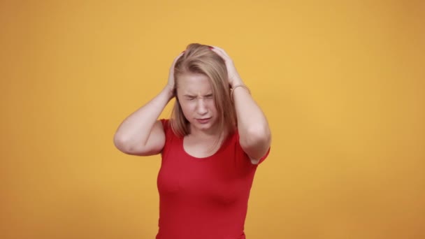 young blonde girl in red t-shirt over isolated orange background shows emotions - Filmati, video