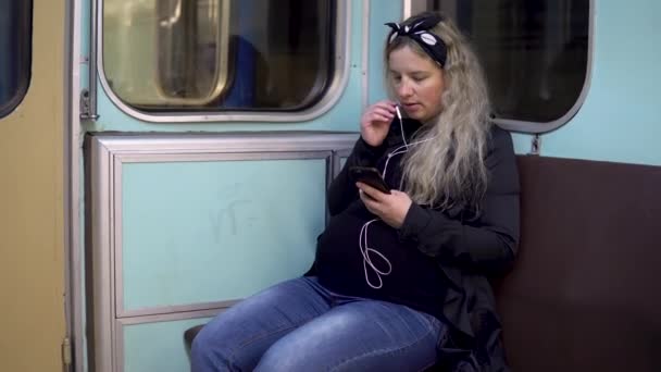 Uma mulher grávida está falando ao telefone através de fones de ouvido para um trem de metrô. Carro velho do trem do metrô
 - Filmagem, Vídeo