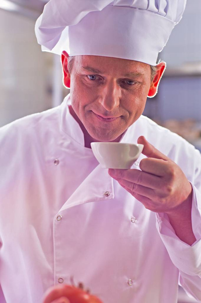 Closeup of confident mature chef smelling food in bowl - Zdjęcie, obraz