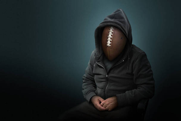 Fútbol americano como la cabeza en el hombre con capucha
 - Foto, imagen
