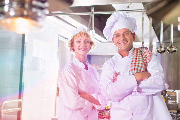 Portrait of confident mature chefs standing with cross arms at kitchen restaurant - Foto, afbeelding