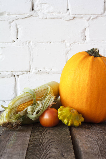Herfst pompoenen en andere groenten op een houten Thanksgiving tafel, witte bakstenen achtergrond, selectieve focus - Foto, afbeelding