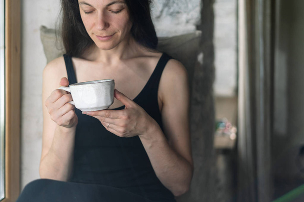 Young adult woman with cup of beverage in hands - Foto, Imagen