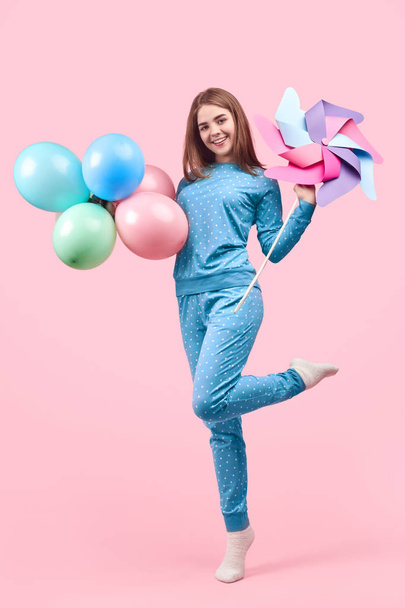 Cheerful childish woman in pajamas celebrating with balloons and pin toy - Zdjęcie, obraz