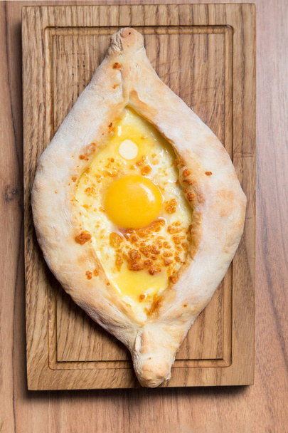 Georgian traditional bread with egg on a wooden table. - 写真・画像
