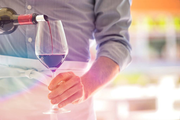 Midsection du serveur versant du vin rouge dans un verre à vin au restaurant
 - Photo, image