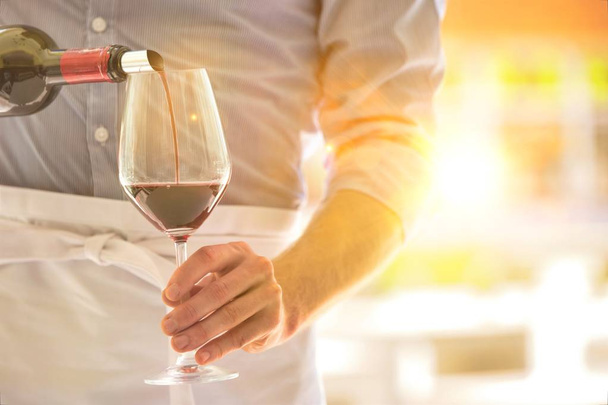 Midsection of waiter pouring red wine in wineglass at restaurant - Photo, image