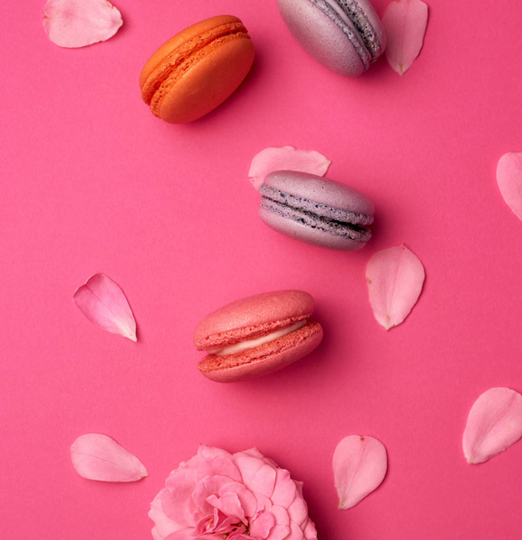 sweet multi-colored macarons with cream and a pink rose bud with - Foto, Imagem