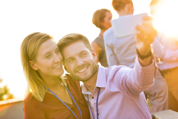 Biznesmen robi selfie z kolegą podczas imprezy na dachu - Zdjęcie, obraz