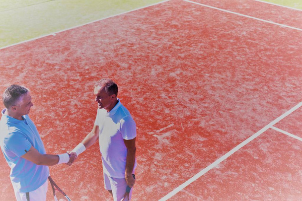 Men greeting while standing on tennis court during summer match - Photo, Image