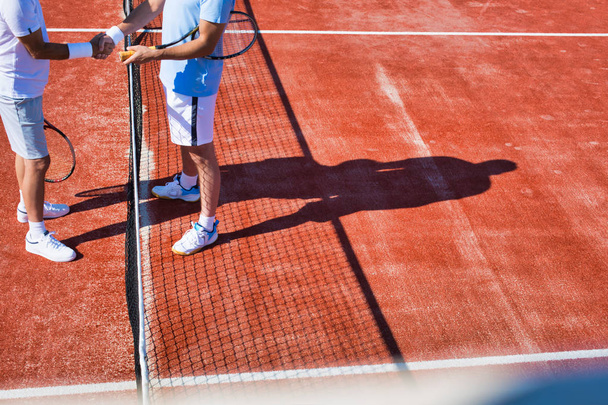 Men greeting while standing on tennis court during summer match - Photo, Image