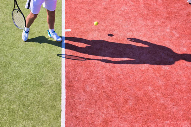 Confident mature man playing tennis on sunny day - Fotografie, Obrázek