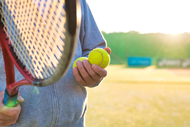 Man holding tenis racket and ball at court on sunny day - 写真・画像