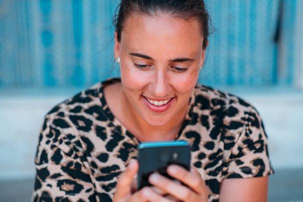 Primo piano di una donna felice che sorride usando uno smartphone all'esterno
. - Foto, immagini
