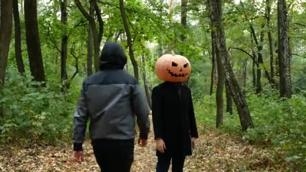 Halloween. A pumpkin-headed man gets in the woods. He pulls out a knife and runs after the victim. - Footage, Video