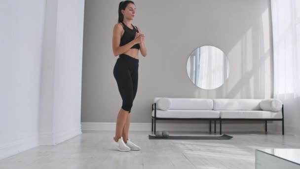 Cheerful sportive woman doing side lunges. Middle-aged happy sportswoman living room doing side lunges and smiling forward while training. - Footage, Video