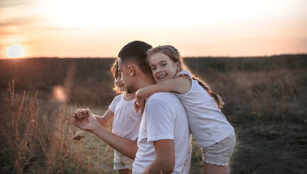 Otec a jeho dcery v terénu při západu slunce . - Fotografie, Obrázek