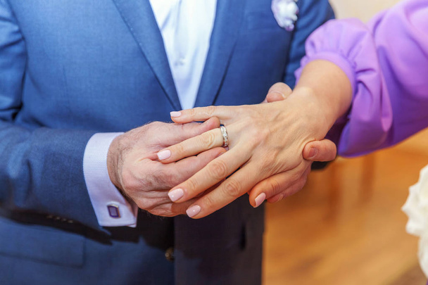 Novio mano poniendo anillo de boda en dedo de novia
 - Foto, Imagen