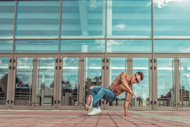 fitness in jump, handstand, sport man dancing break dance, naked torso inflated, young guy, free space text lifestyle motivation, summer in city background glass building window, in motion - Φωτογραφία, εικόνα