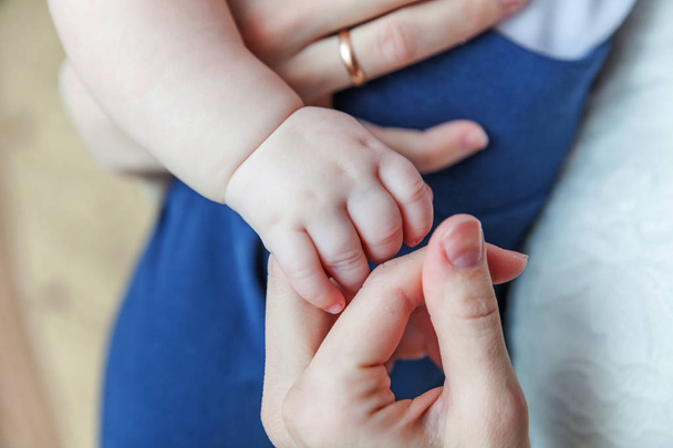 小さな新生児の男性または女性の赤ちゃんの手は、母の指を保持 - 写真・画像