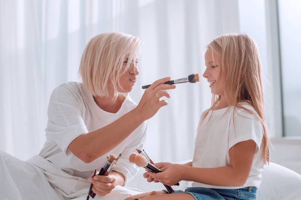 close up. mom and little daughter playing with makeup brushes - Φωτογραφία, εικόνα