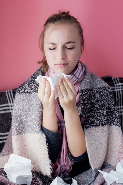 Horizontal portrait young girl with a handkerchief and runny nose in profile, sneezing from flu, white skinned female model at pink wall. Healthcare and medical concept. - Foto, Imagen