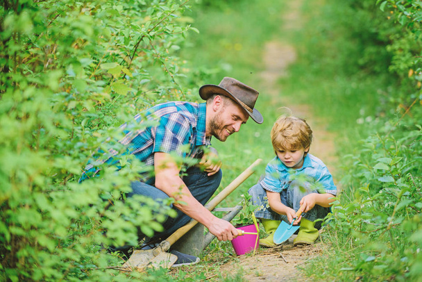 Little helper in garden. Farm family. Little boy and father in nature background. Gardening tools. Gardening hobby. Dad teaching little son care plants. Spring gardening routine. Planting flowers - Foto, Imagem