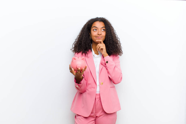 young pretty black woman with a piggy bank against white wall - 写真・画像
