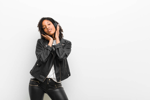 young pretty black woman listening music with a headphones wearing a leather jacket against white wall - Fotografie, Obrázek